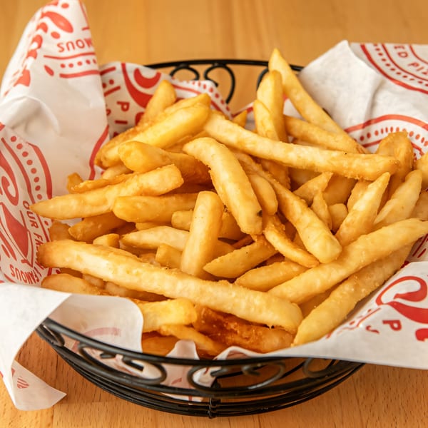 A basket of golden, crispy french fries from Sicilia's Pizzeria, served in a paper-lined basket.