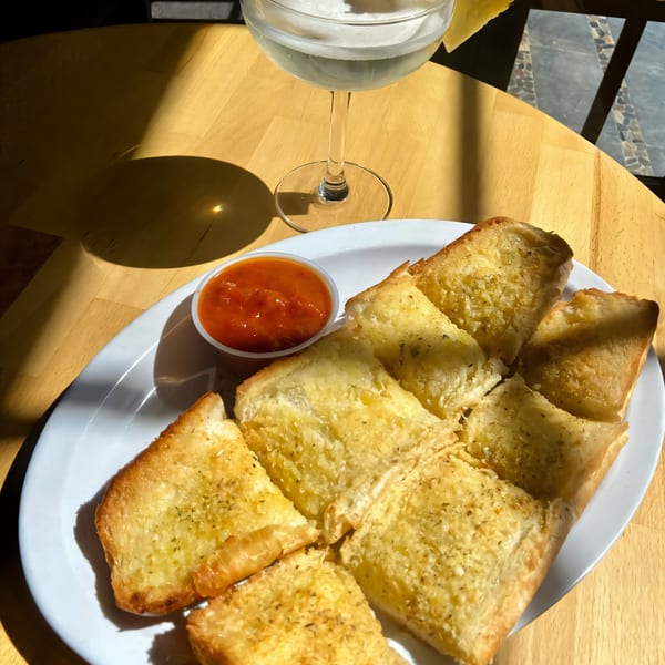 Garlic bread with marinara sauce and a cocktail on a wooden table at Sicilia's Pizzeria.